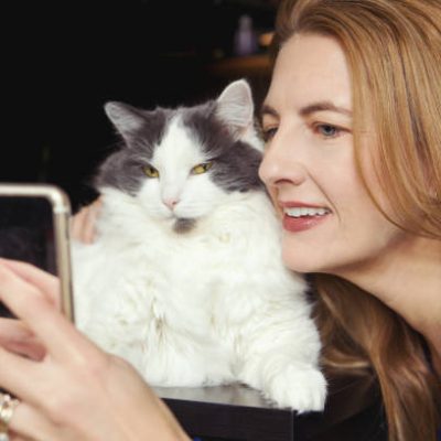A woman taking a cheek to cheek selfie with her cat.